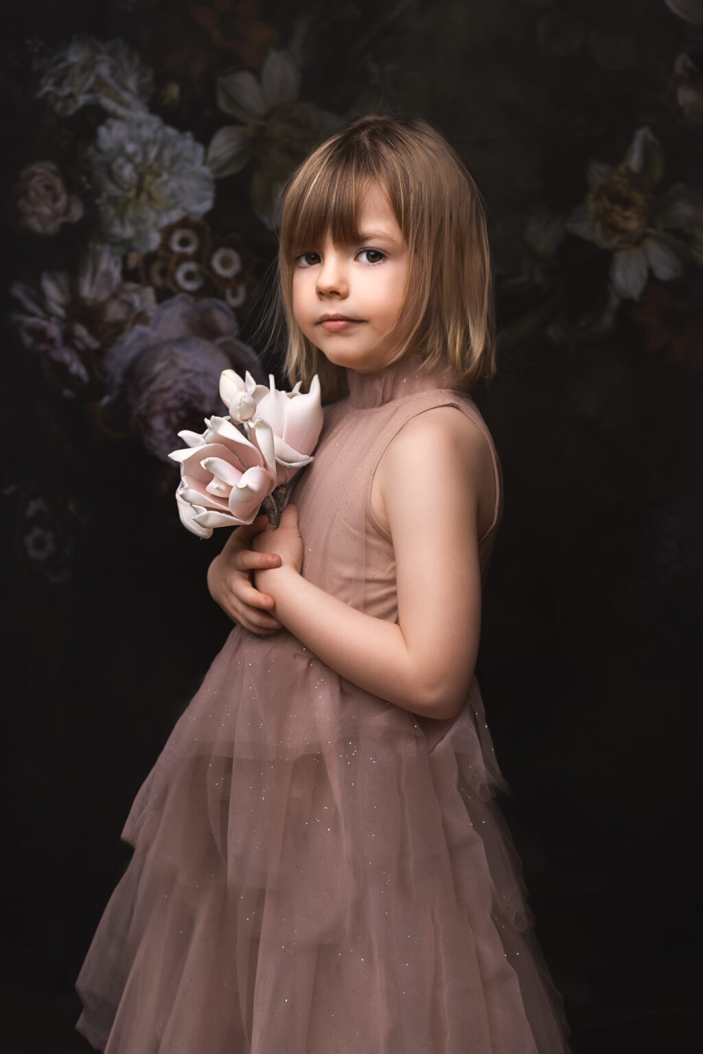 Petite fille de 5 ans qui tient des fleurs dans une jolie robe de princesse