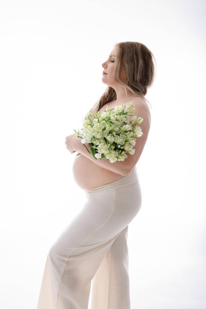 photo contre jour maman enceinte de 7 mois qui tient des fleurs