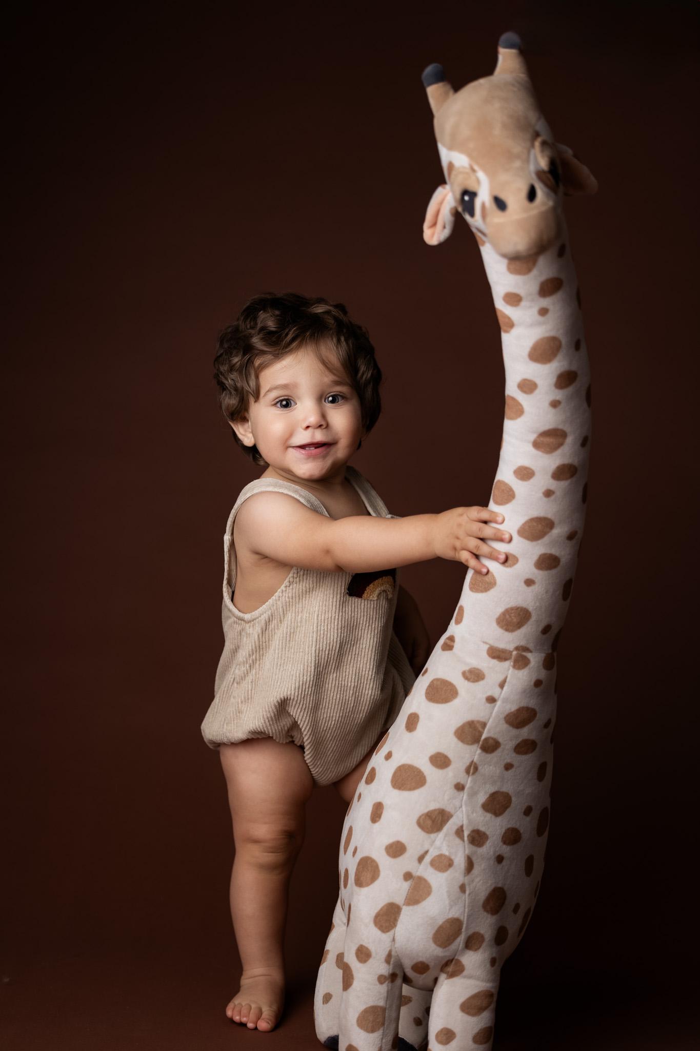bébé 1 an avec sa peluche girafe se tient debout