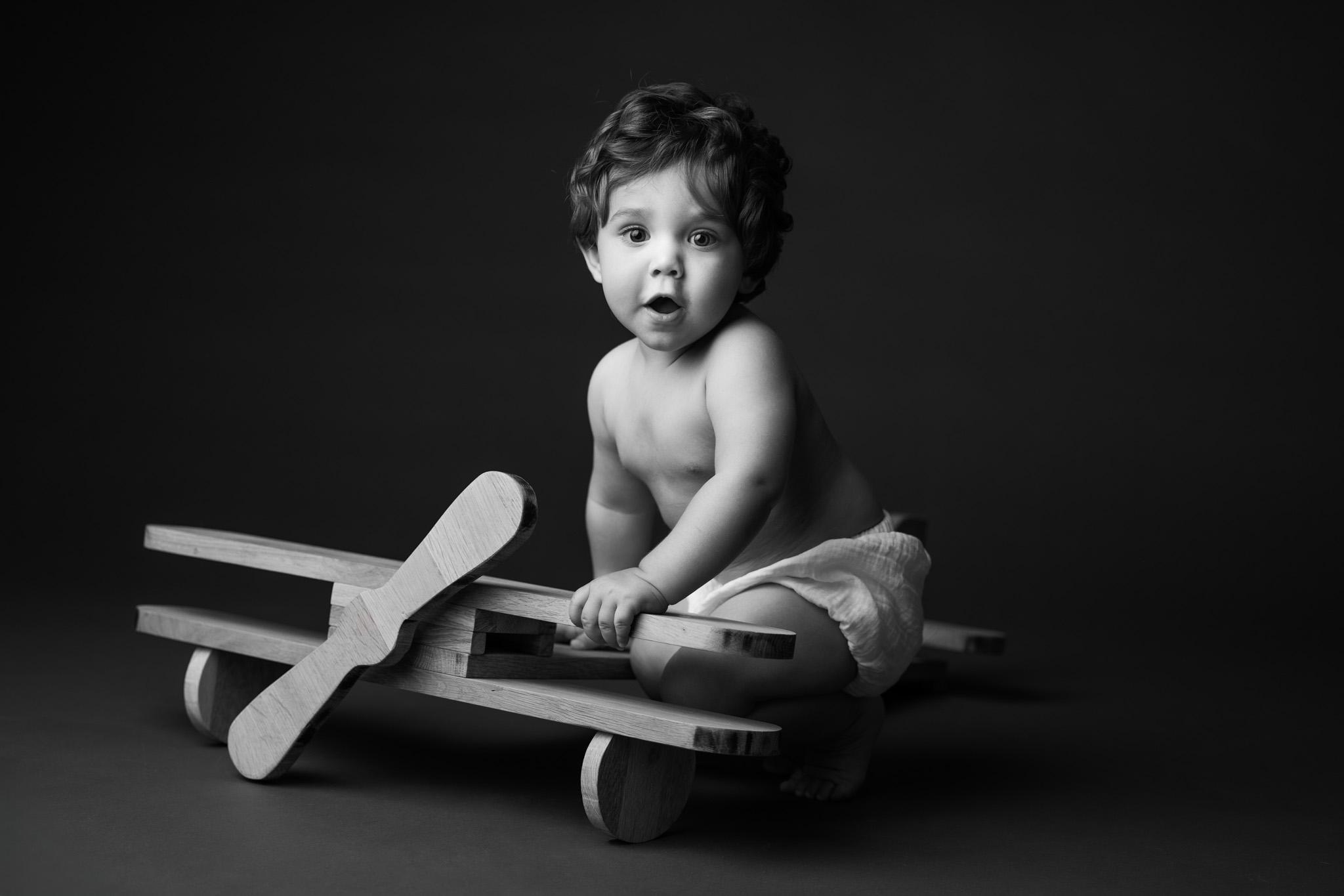 bébé 1 an assis sur son avion en bois