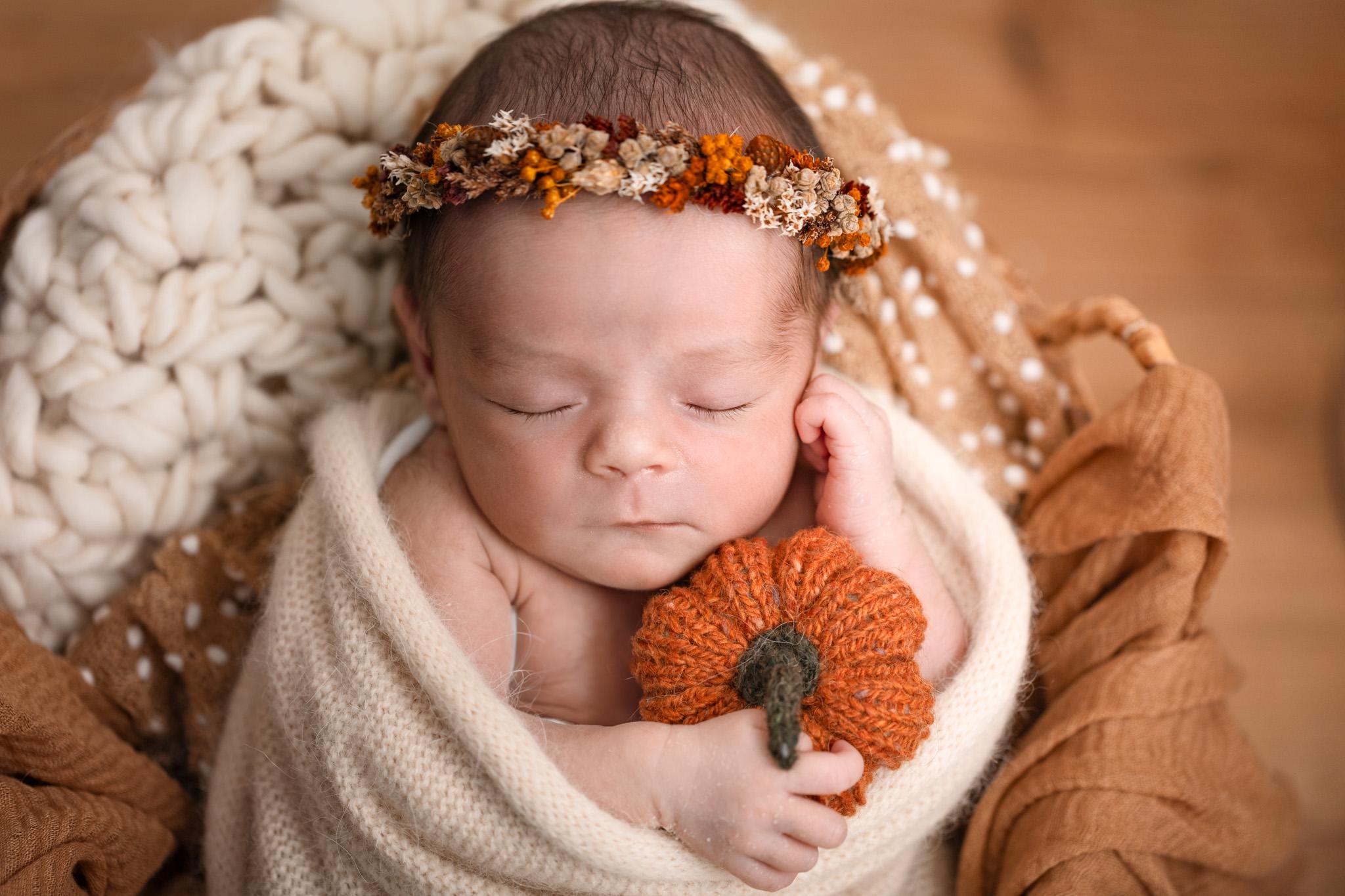 bébé dans un décor automnale avec une petite couronne et citrouille orangé